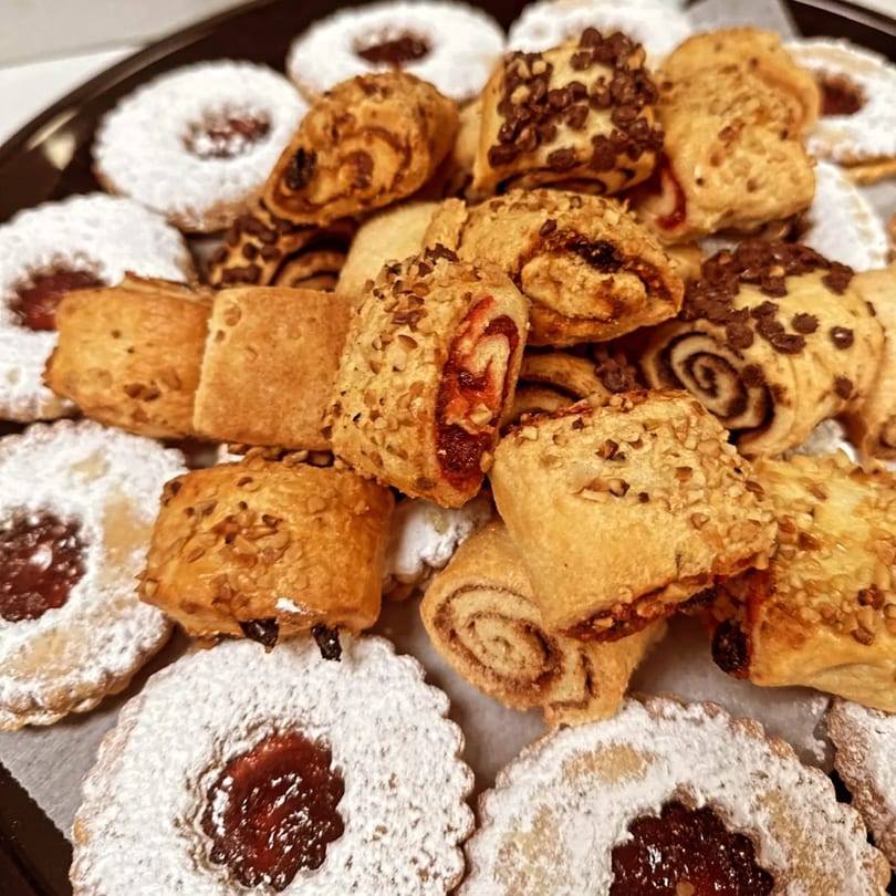Close-up of a tray filled with assorted Italian deli pastries, some with powdered sugar, nuts, or chocolate.